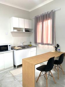 a kitchen with a wooden table and two chairs at Studio Aconchegante e Moderno in Castanhal
