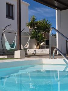 a swimming pool with a hammock next to a house at Casa Sunny in Yaiza