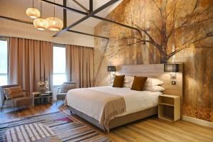 a bedroom with a large bed and a tree mural at Walnut Bistro & Suites in Eymet