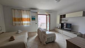 a living room with two beds and a television at Monolocale in centro con parcheggio privato! in Palau
