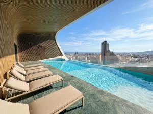 a swimming pool on the roof of a building with chairs at 21st Floor Sunset Apartment - Mercury Tower with Pool Access by Stays Uniq in St. Julianʼs