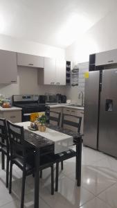 a kitchen with a table with chairs and a refrigerator at Cozy Escape 876 Secure 2BR with AC, Parking & near Beaches in Portmore