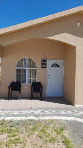 two chairs sitting outside of a building with a door at Cozy Escape 876 Secure 2BR with AC, Parking & near Beaches in Portmore