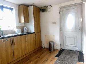 a kitchen with wooden cabinets and a door at Compact single room A near Heathrow with 24 hour buses to all terminals in Feltham