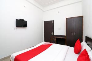 a bedroom with a bed with red pillows and a tv at Hotel O by OYO Mid Town Ojus Tower in Rudrapur