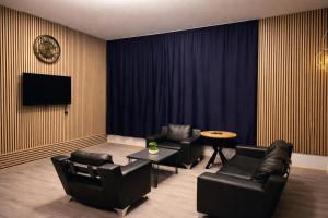 a living room with black leather furniture and a tv at ATAKORU Suit in Alacaatlı