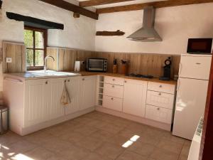 a kitchen with white cabinets and a sink and a microwave at La maisonnette de la venelle in Chaunay