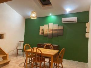 a dining room with a green wall with a table and chairs at La maisonnette de la venelle in Chaunay +2 photos