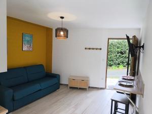 a living room with a blue couch and a table at Le Nautile - petit déjeuner - 10mn du Parc in Treize-Vents