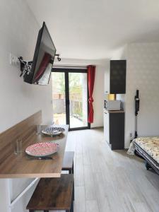 a living room with a table and a tv on the wall at Le Nautile - petit déjeuner - 10mn du Parc in Treize-Vents