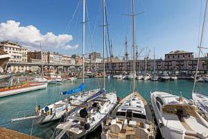 een groep boten aangemeerd in een haven met gebouwen bij Sull'Acqua del Porto Antico in Genua