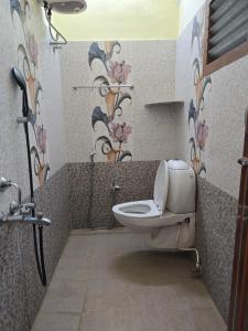 a bathroom with a toilet and flowers on the wall at Yercaud Misty Haven in Yercaud