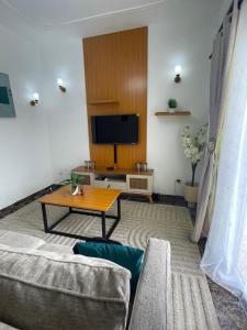a living room with a table and a tv at Cozy loft Bonamoussadi Douala in Douala
