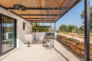 a patio with a table and chairs and a stone wall at Uma Casa Rural in Santa Bárbara de Nexe