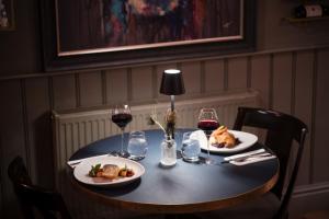 a table with two plates of food and wine glasses at Flower Pot Hotel in Henley on Thames +28 photos