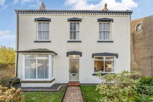 a white house with black windows and a brick driveway at 3 Bed in Gosforth oc-s34885 in Gosforth