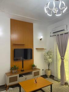 a living room with a tv and a table at Cozy loft Bonamoussadi Douala in Douala +2 photos