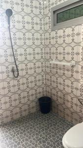 a bathroom with a white tiled wall with a shower at Cozy loft Bonamoussadi Douala in Douala