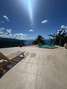 a bench on a patio with a view of the ocean at Bas de Villa Tropical Soul in Pointe-Noire