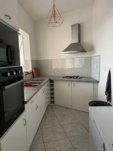 a kitchen with white cabinets and a stove top oven at Bas de Villa Tropical Soul in Pointe-Noire +4 photos