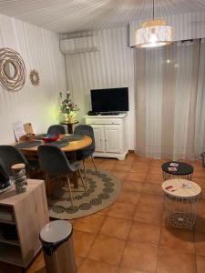 a living room with a table and chairs and a television at studio cabine. Terrasse in Le Lavandou