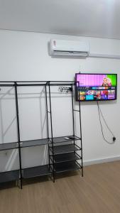 a room with a tv on a wall with glass shelves at Flat Equipado no Centro - Conforto in Governador Valadares