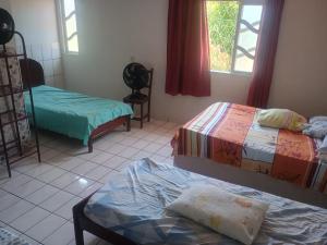 a room with two beds and a table and windows at Casa da Vovó Ivete in Guarapari