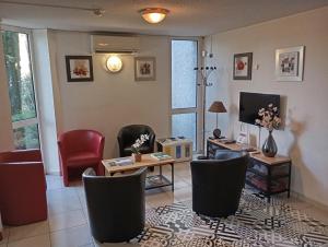 a living room with chairs a table and a tv at HOTEL RESTAURANT OLYMPE in Aix-en-Provence