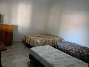 a room with two beds and a dresser at Casa da Vovó Ivete in Guarapari