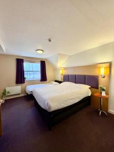 a hotel room with two beds and a window at Premier Nights, Wigan, Standish M6 J27 in Standish
