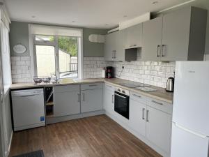 a kitchen with white cabinets and a window at Crianlarich Cottage in Fort Augustus