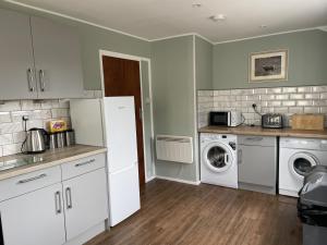 a kitchen with a refrigerator and a washer and dryer at Crianlarich Cottage in Fort Augustus +8 photos