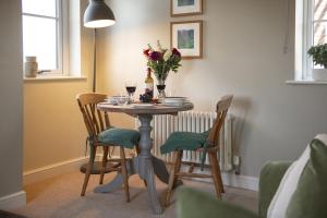a dining room table with wine glasses and flowers on it at Green Balk Cottage in Stokesley
