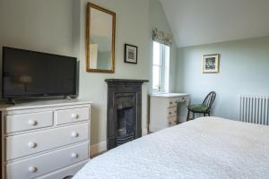 a bedroom with a bed and a tv and a fireplace at Green Balk Cottage in Stokesley