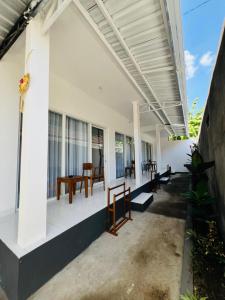 a porch of a white house with a table and chairs at Ina Guesthouse in Lovina