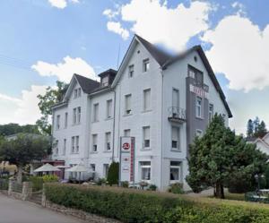 a large white building with a sign in front of it at Hotel W Wolfsschlucht in Baden-Baden