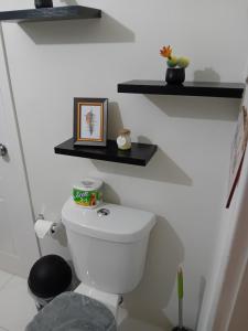 a bathroom with a toilet with shelves on the wall at Cozy Escape 876 Secure 2BR with AC, Parking & near Beaches in Portmore +29 photos
