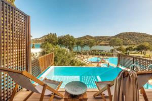 a swimming pool with two chairs and a table on a balcony at Zeus Dolce by Wyndham Athens in Vravrona