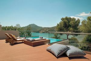 a deck with chairs and a pool with a view of the water at Zeus Dolce by Wyndham Athens in Vravrona +140 photos