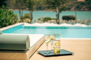 two glasses of wine on a tray next to a pool at Zeus Dolce by Wyndham Athens in Vravrona
