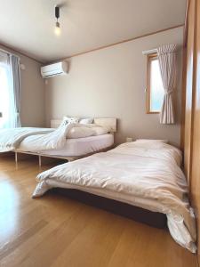a bedroom with two beds and a window at Cozy House Azumino in Azumino