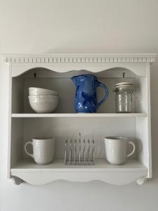 a white shelf with cups and utensils on it at The Stables in Corsley