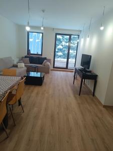 a large living room with a couch and a tv at Lyra Forest Apartment in Borovets