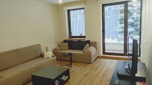 a living room with a couch and a tv at Lyra Forest Apartment in Borovets