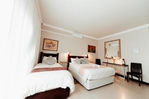 a bedroom with two beds and a mirror at Mi Vida Guesthouse in Klerksdorp
