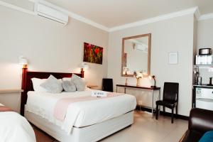 a bedroom with a large white bed and a mirror at Mi Vida Guesthouse in Klerksdorp