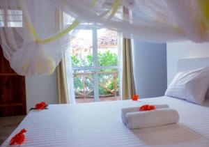 a bedroom with a white bed with red flowers on it at Datch Hideaway in Kiwengwa