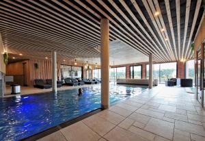 a large swimming pool in a building with a large ceiling at La Briqueterie in Saint-Aubin