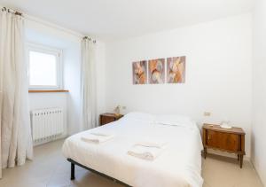 a white bedroom with a bed and a window at Casa di Montagna tranquilla e spaziosa in Serina