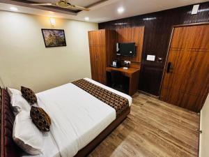 a bedroom with a bed and a tv and a door at Hotel Downtown in Jamshedpur +24 photos